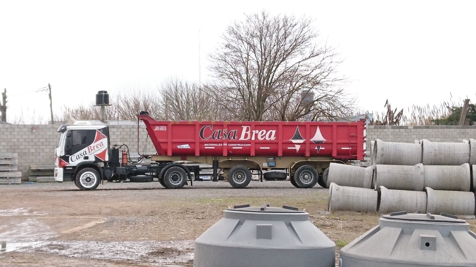 El semirremolque rojo de Casa Brea con el logotipo pintado, cargado en el corralón.