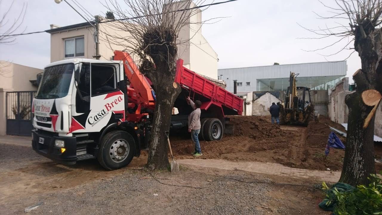 Un camión con hidrogrúa de Casa Brea descargando material en una obra.